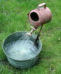 Old sprinkling can with water flowing into a wash basin